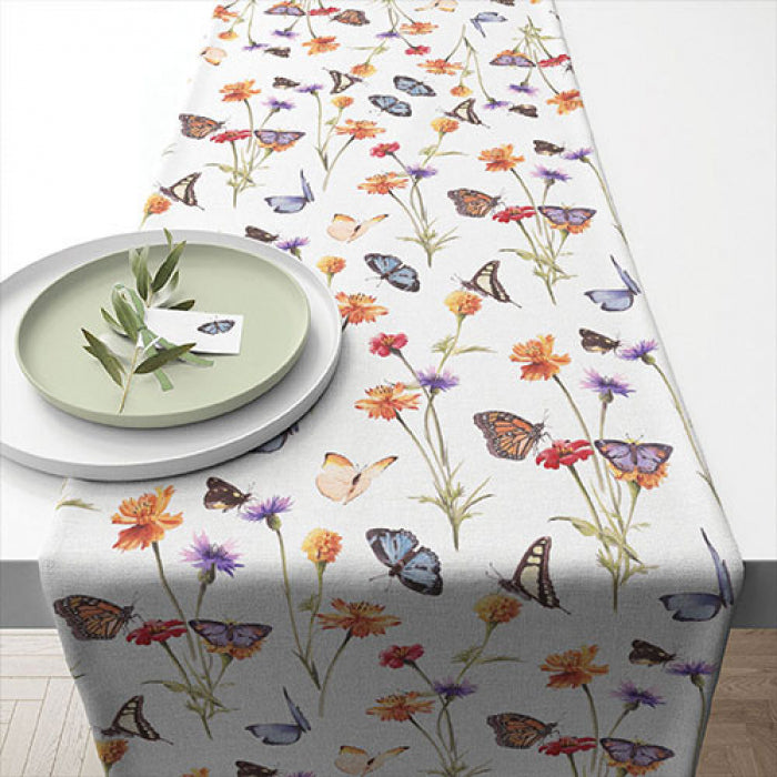 Toalha de mesa branca com padrão colorido de borboletas e flores.