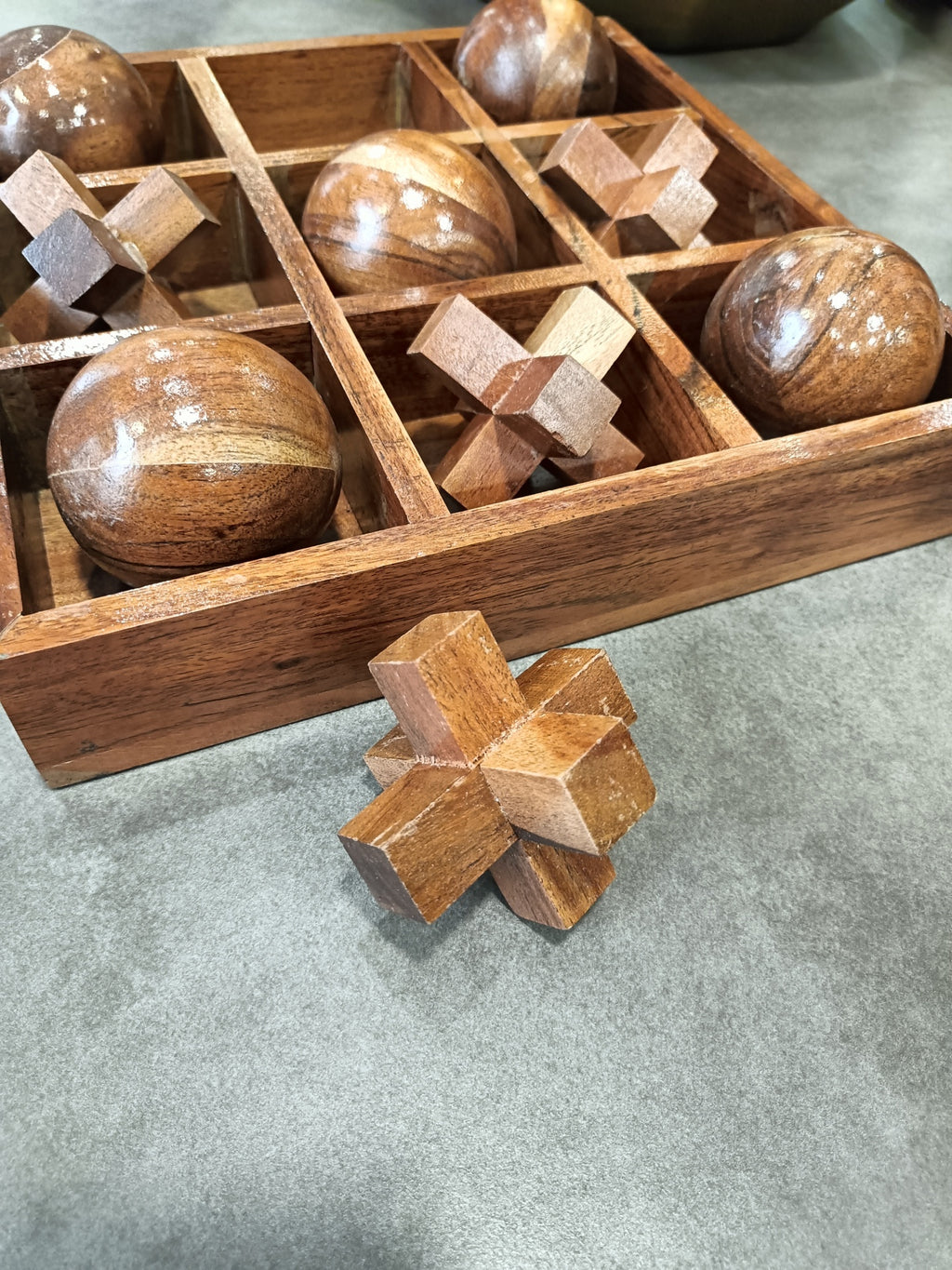 Jogo de três em linha em madeira com tabuleiro, bolas e peças de madeira entrelaçadas.