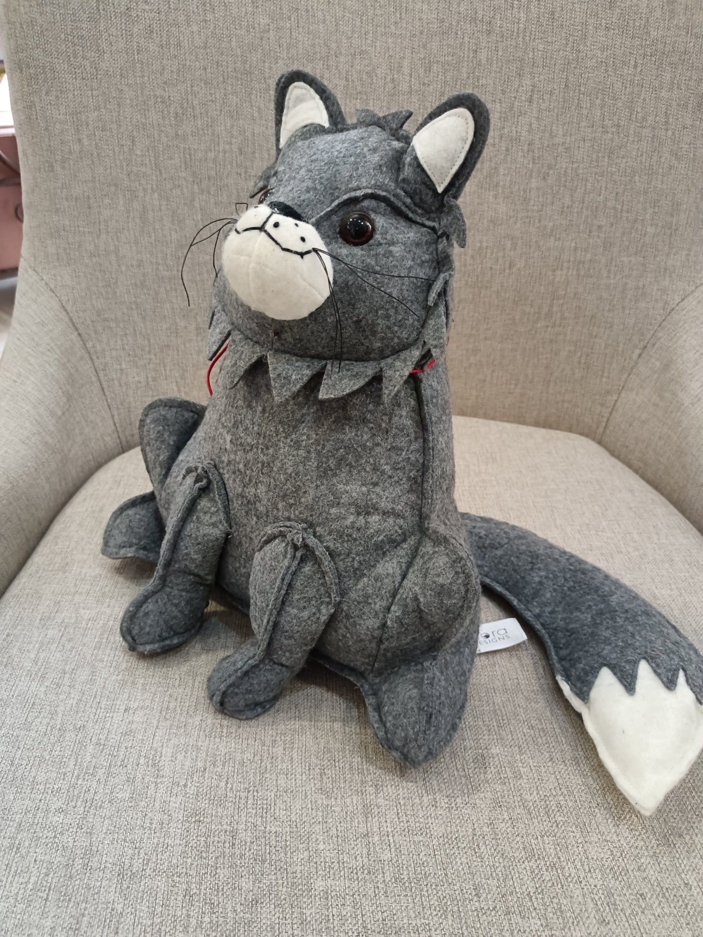 Pelucha de lobo cinzento sentada numa cadeira cinzenta