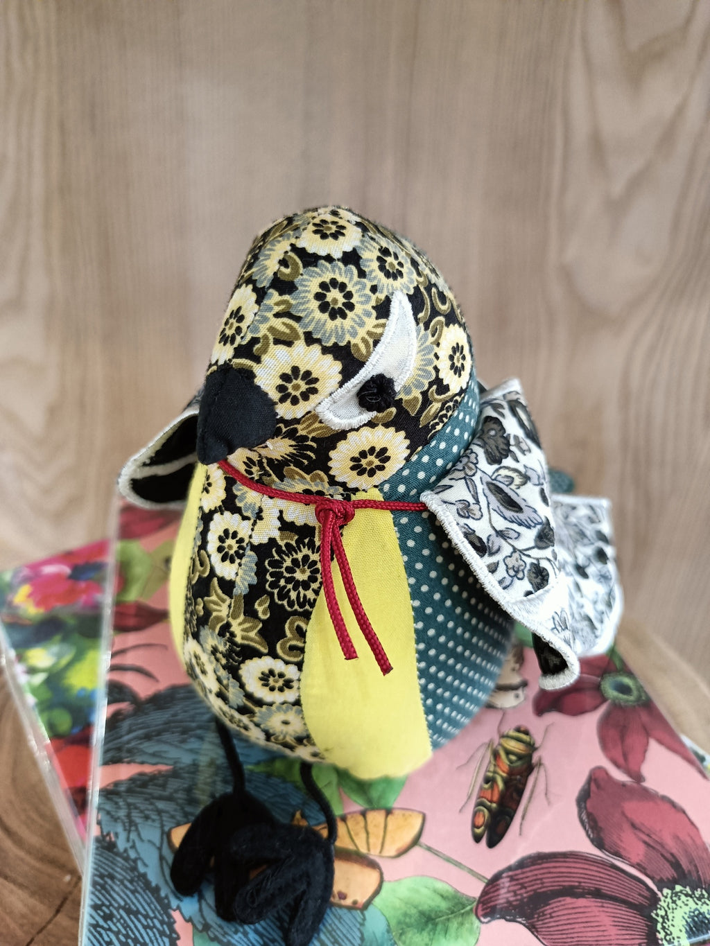 Pássaro decorativo em tecido com padrão floral amarelo e preto
