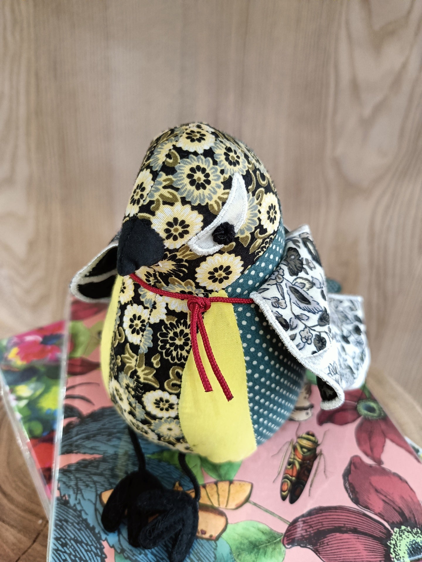 Pássaro decorativo em tecido com padrão floral amarelo e preto