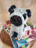 Boneco de cão de lã sentado em cadernos florais sobre base de madeira