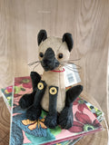 Boneco de peluche castanho claro e preto em cima de agendas coloridas com flores.