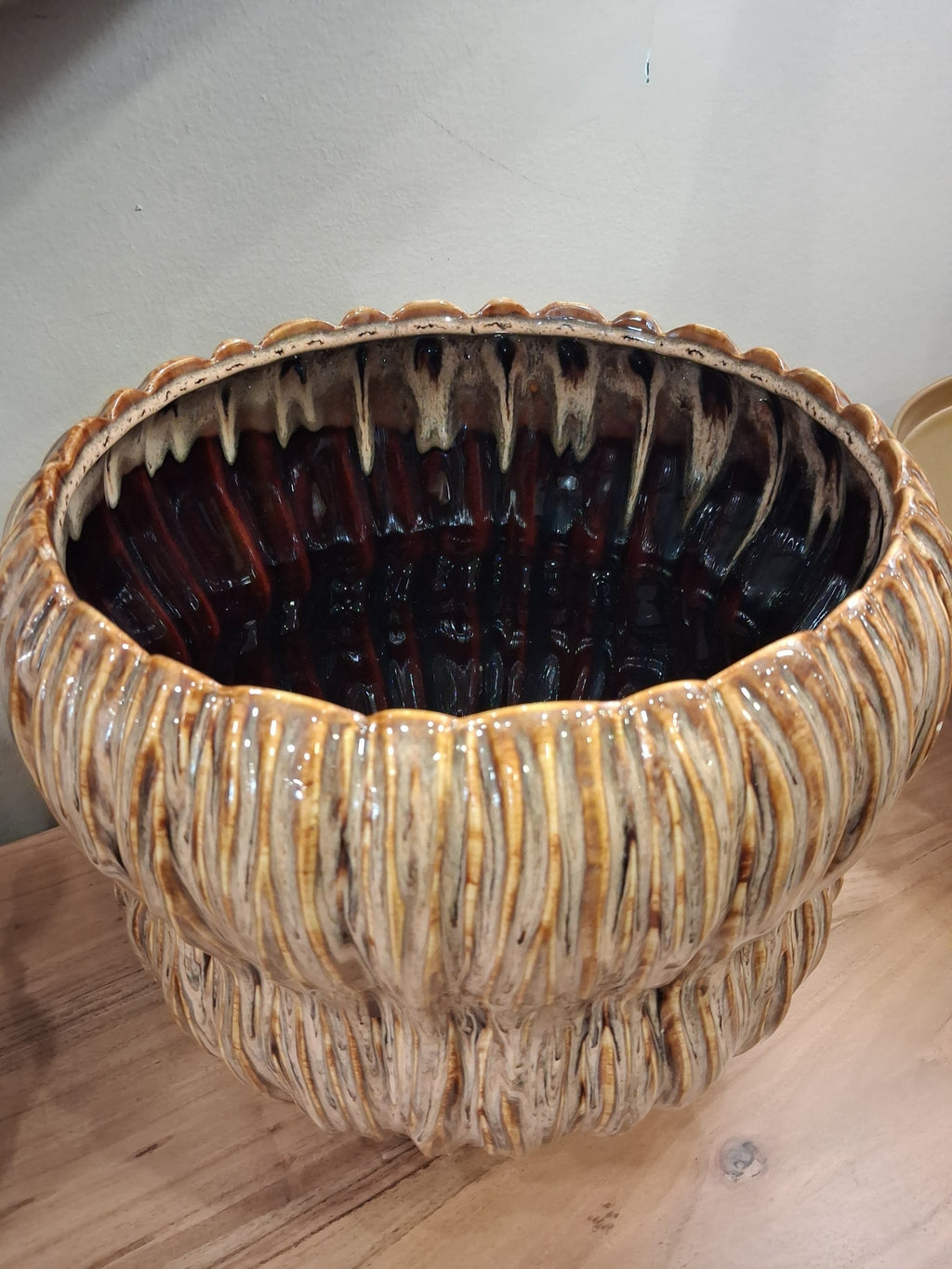 Vaso cerâmico castanho claro com interior vidrado castanho escuro, colocado sobre mesa de madeira.