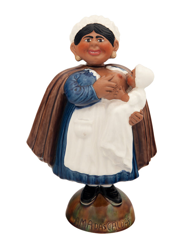 Estatueta de mulher a segurar bebé com base onde está escrito MAMÃ DAS CALDAS