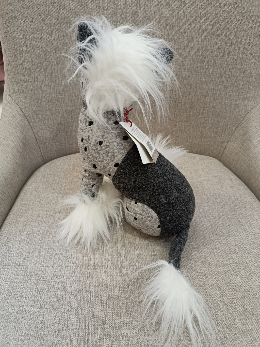 Peluche de cão cinzento e branco sentado em cadeira bege