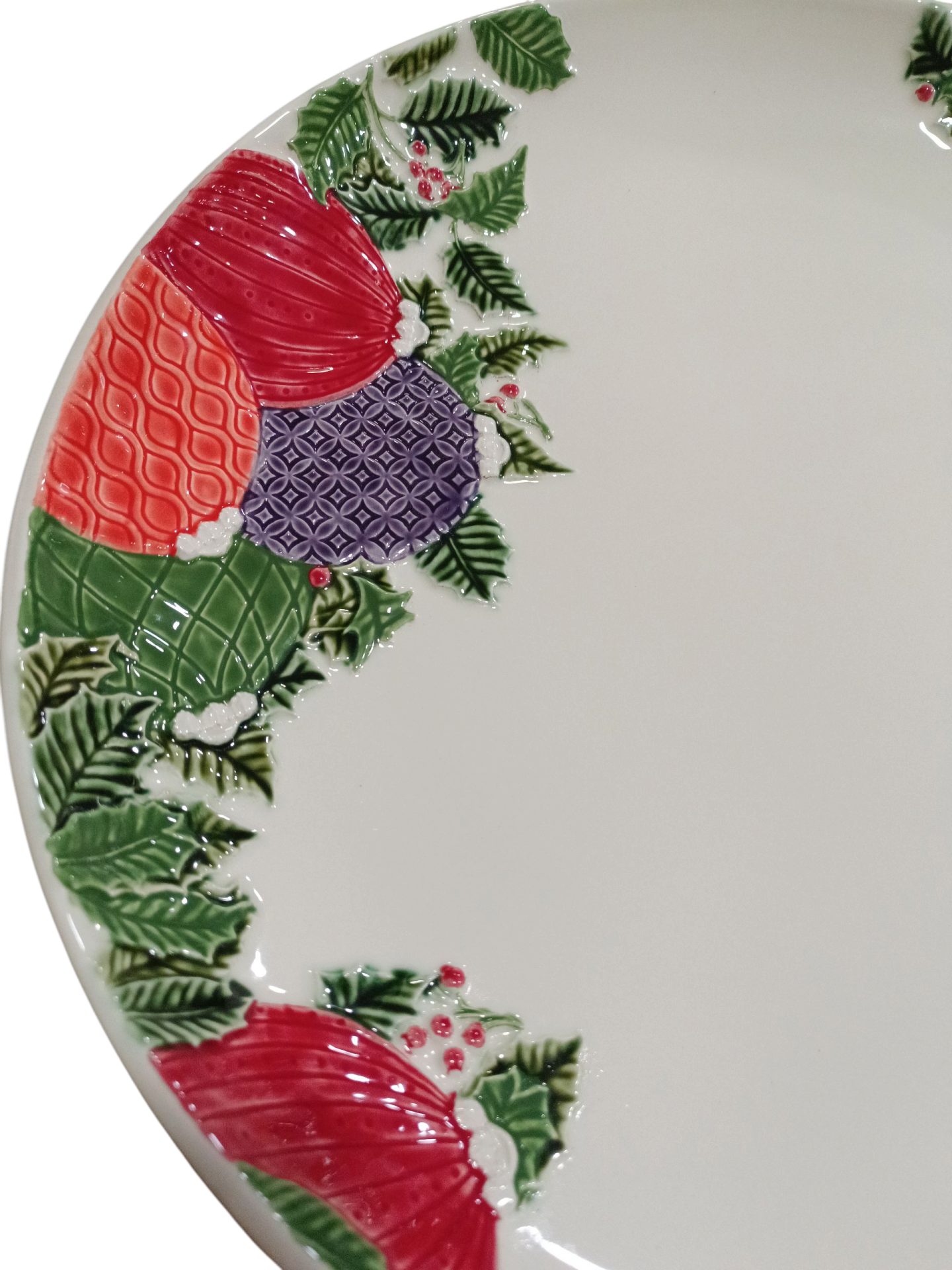 Prato de cerâmica branca com decoração em relevo de pinhas coloridas e ramos verdes com bagas vermelhas.