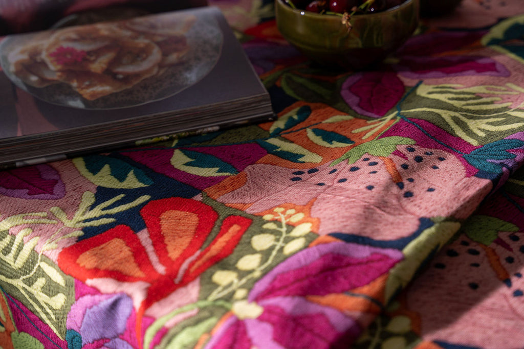 Toalha de mesa com padrão floral colorido e objetos em cima