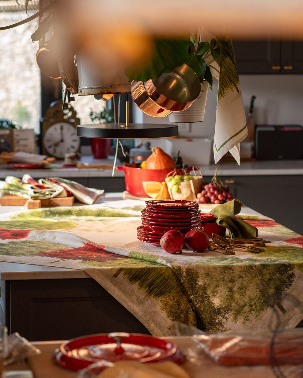 Mesa de cozinha com loiça vermelha e frutas frescas sobre toalha colorida