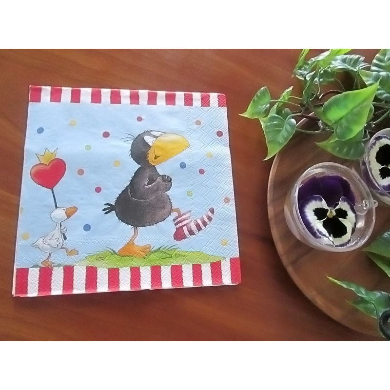 Guardanapo decorativo com desenho de corvo e pato, bolinhas coloridas e riscas vermelhas e brancas na borda.