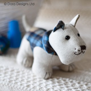 Boneco de cão em tecido cinza com casaco azul às riscas sobre superfície branca
