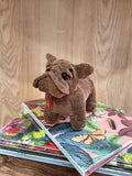 Pelúcia de cão marrom sobre livros coloridos com padrões florais e de borboletas