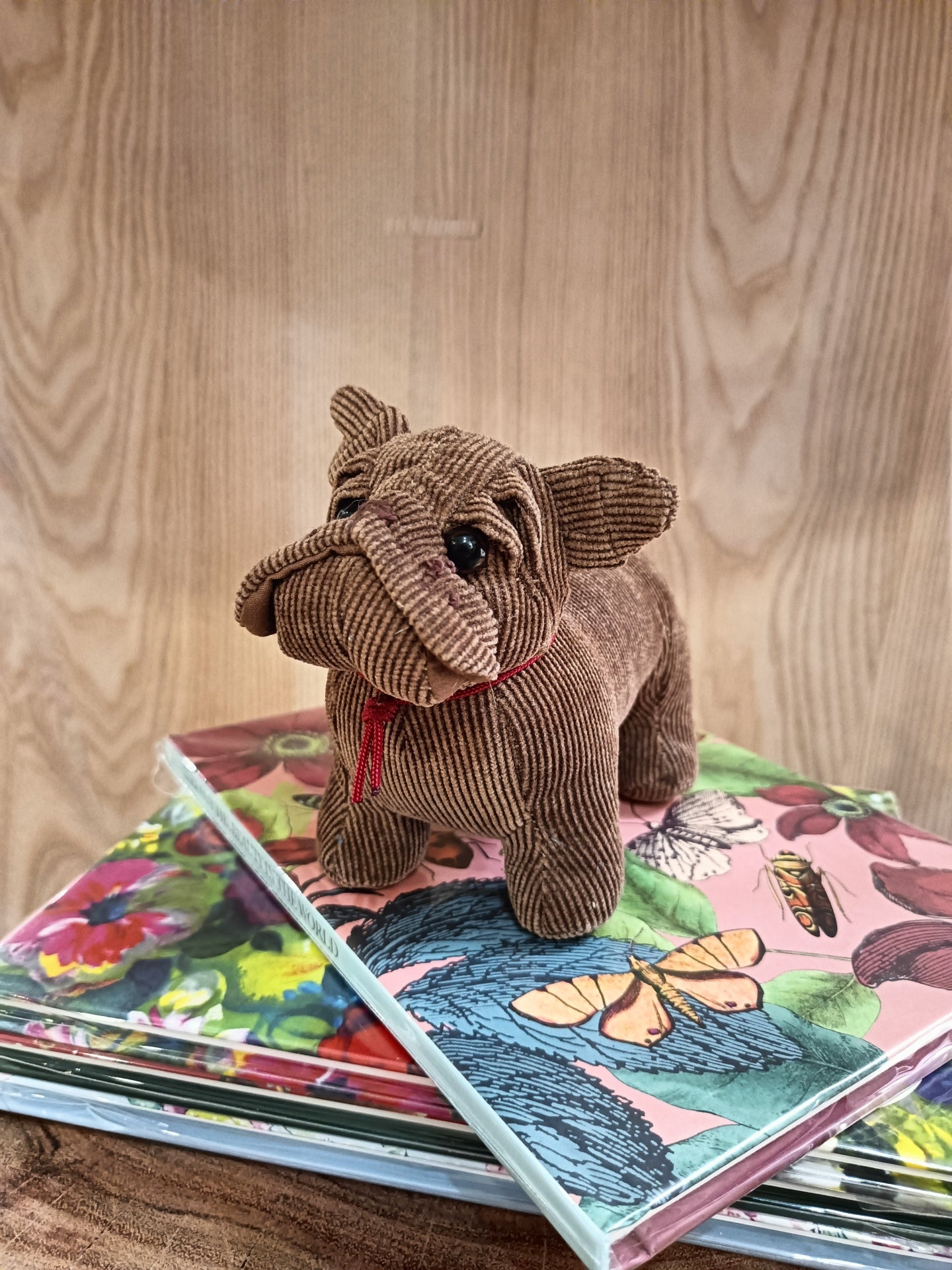 Pelúcia de cão marrom sobre livros coloridos com padrões florais e de borboletas
