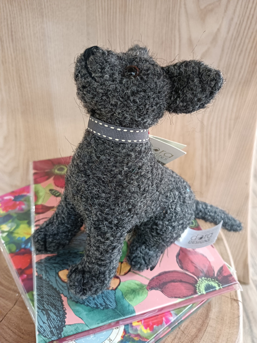 Cão decorativo tecido cinzento escuro sentado sobre caixas florais