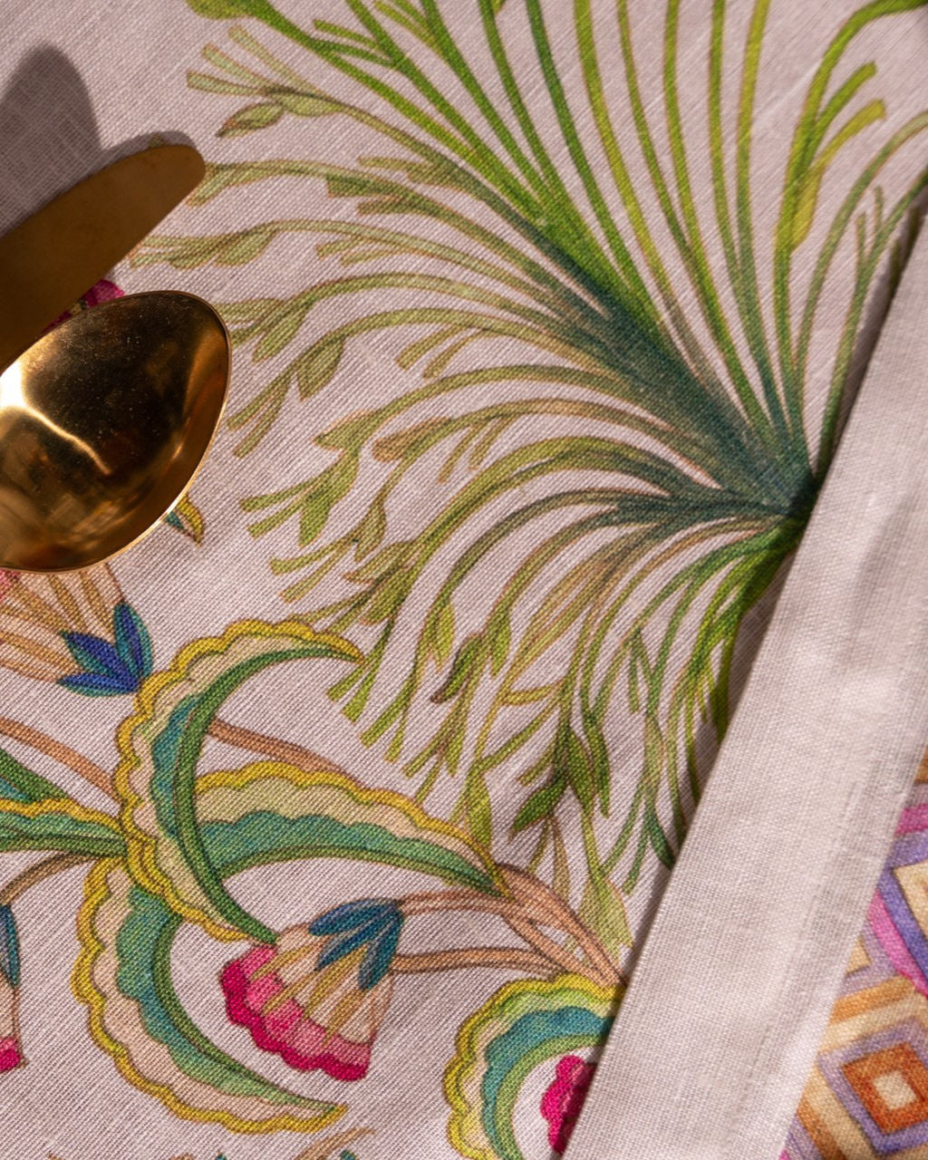 Pano de mesa com padrão floral colorido e talheres dourados