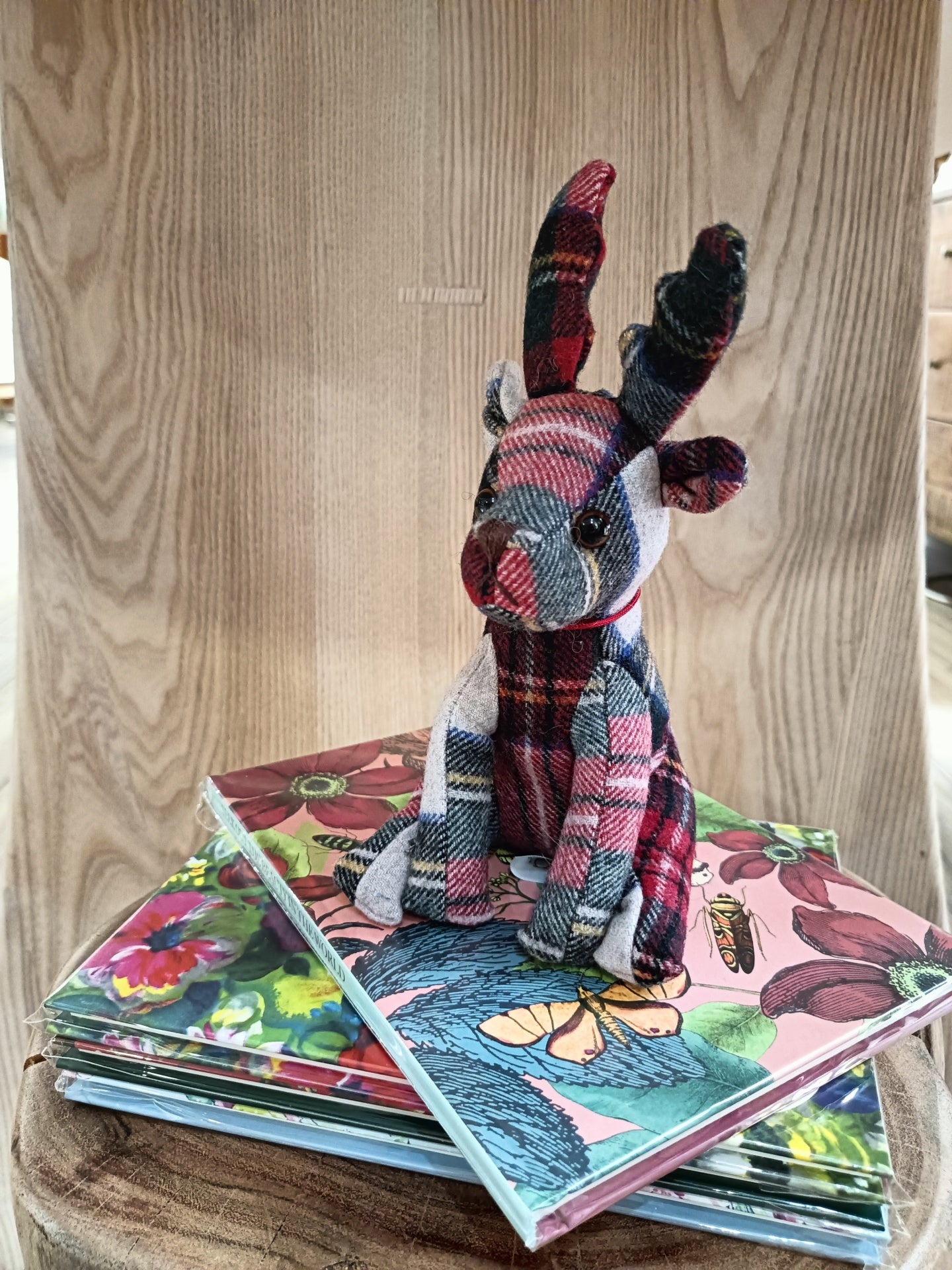 Boneco de rena xadrez sobre livros com capas florais