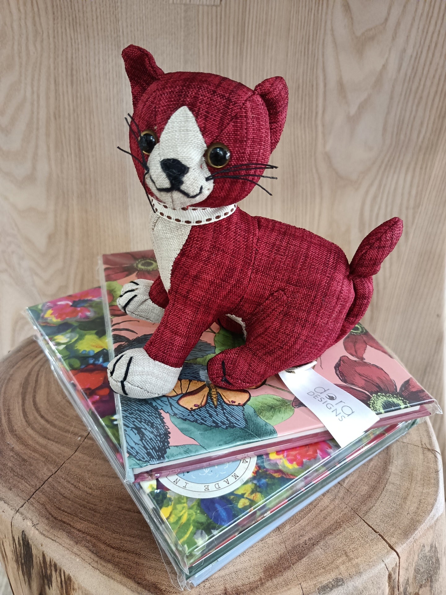 Boneco de gato de tecido vermelho sobre cadernos de flores