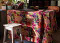 Mesa decorativa com toalha estampada colorida e banco de madeira