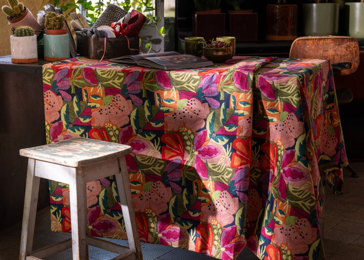 Mesa decorativa com toalha estampada colorida e banco de madeira
