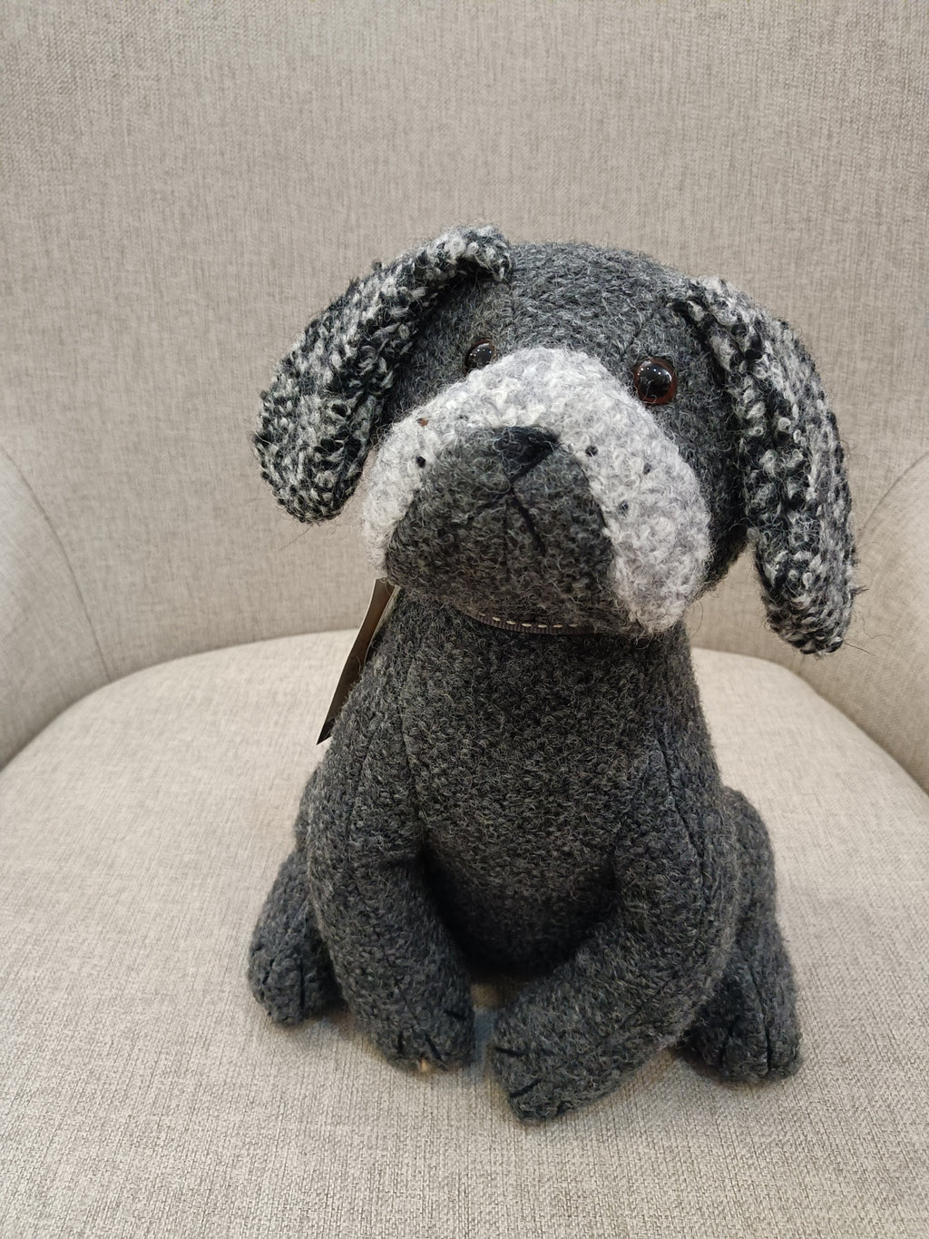 Boneco de cão cinza sentado numa cadeira cinza claro