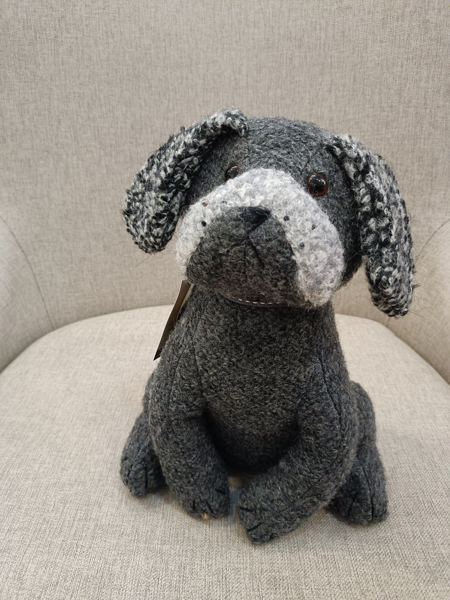 Boneco de cão cinza sentado numa cadeira cinza claro
