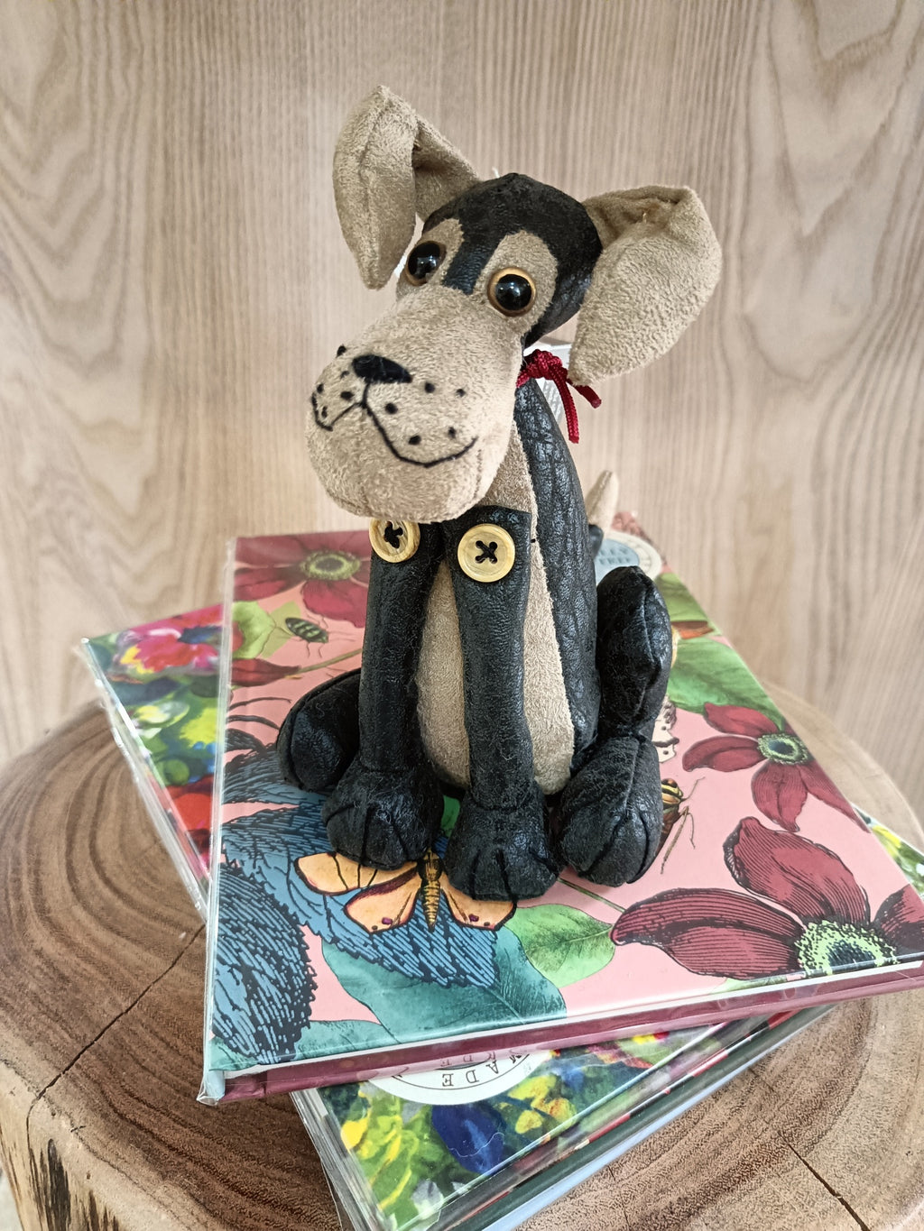 Boneco de cão de tecido sentado em cadernos florais sobre superfície de madeira