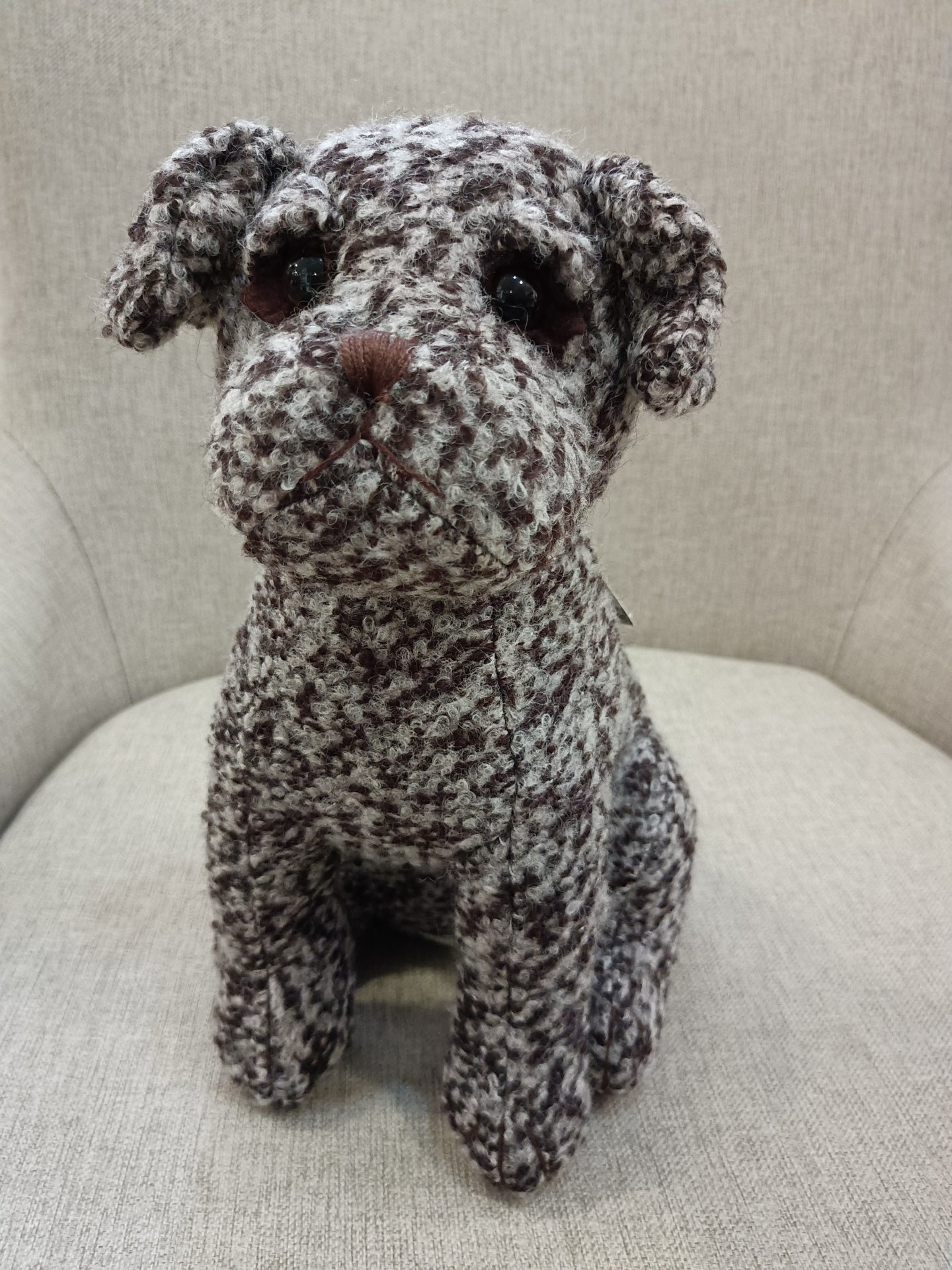 Boneco peluche cão tecido cru castanho em cadeira cinza