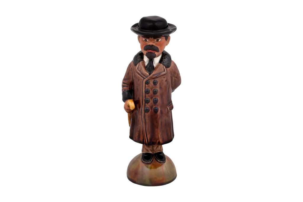 Estatueta de homem com sobretudo castanho e chapéu preto com bengala
