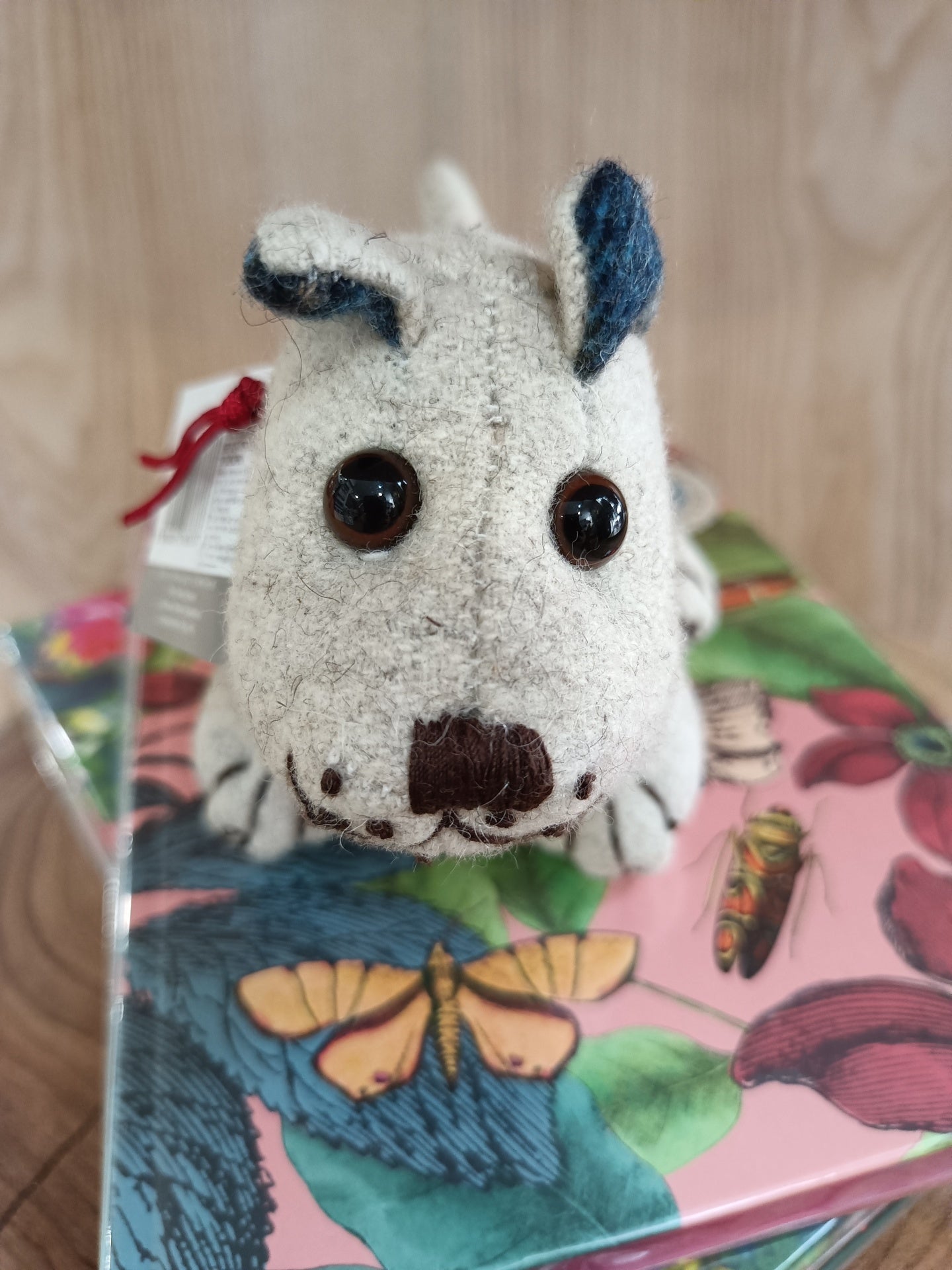 Brinquedo de cão de tecido sobre caixa decorada com borboleta e flores
