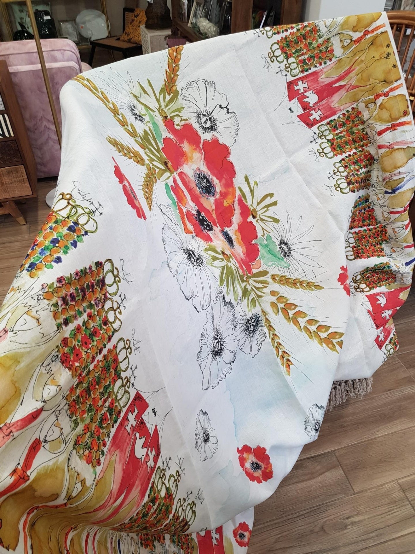 Manta decorativa branca com padrão floral colorido sobre móvel