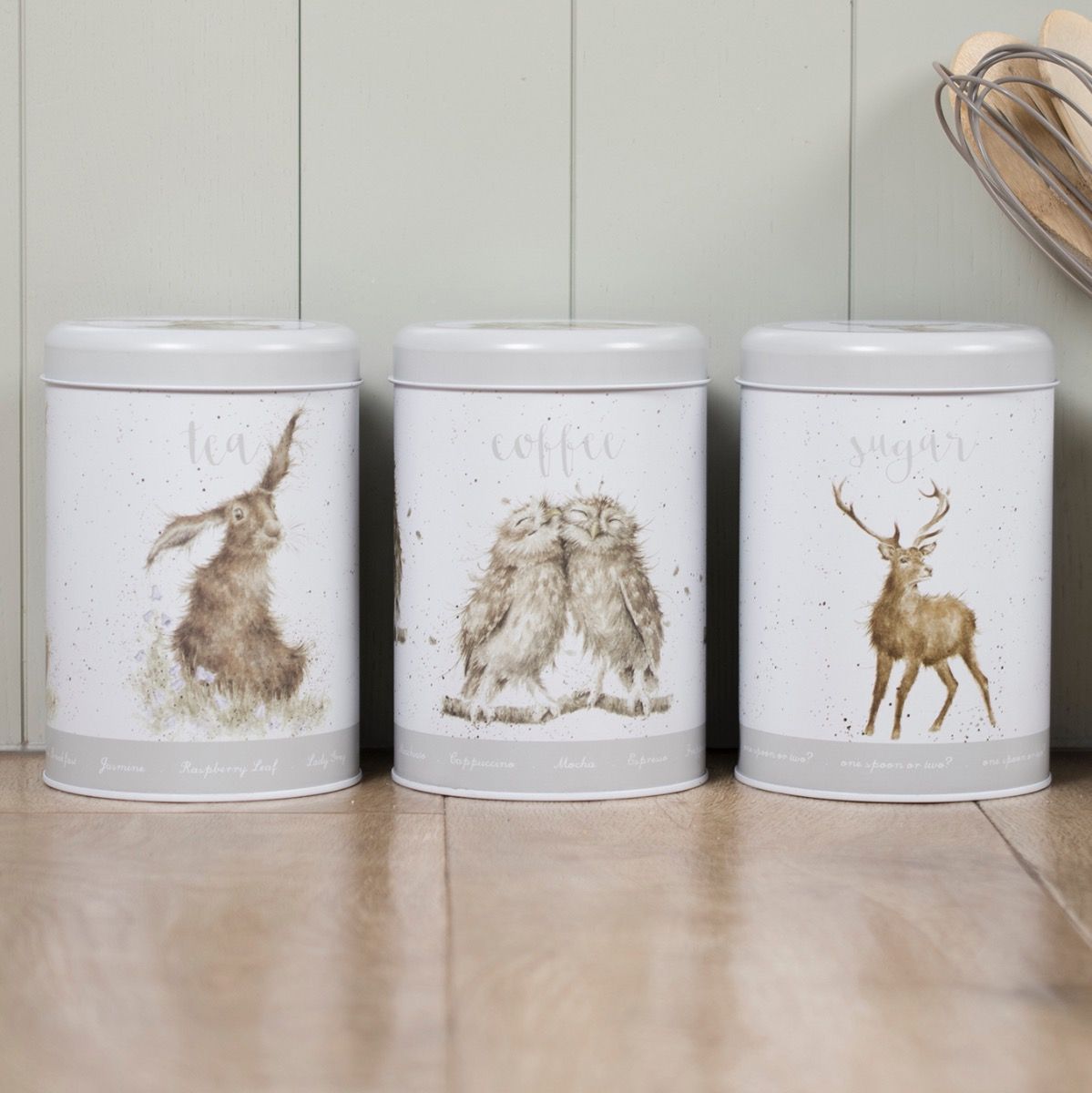 Três latas decorativas brancas com ilustrações de animais e texto para chá, café e açúcar