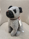 Boneco de cão cinza e preto sentado numa cadeira cinzenta clara