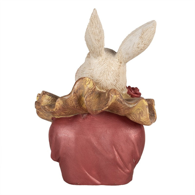 Figurinha decorativa de coelho vista de costas com casaco vermelho e colar dourado
